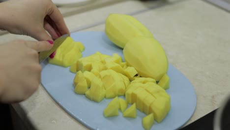 Frau-Schneidet-Kartoffeln-Auf-Dem-Blauen-Schneidebrett