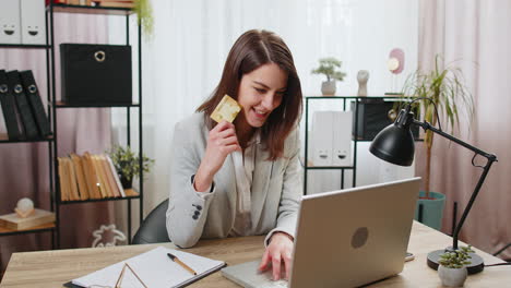 Business-woman-using-bank-credit-card-and-laptop-for-online-shopping-bill-payments-at-home-office