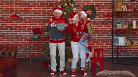 Cheerful-old-grandparents-with-granddaughter-child-kid-dancing-at-home-near-decorated-Christmas-tree