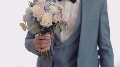 Handsome-groom-with-beautiful-wedding-bouquet.-Light-background