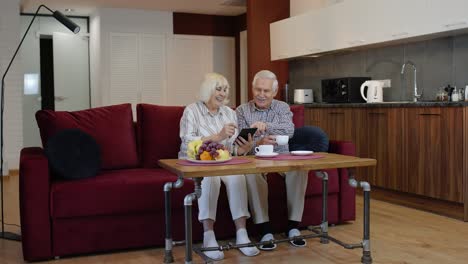 Älteres,-Altes-Großelternpaar,-Das-Zu-Hause-Mit-Einem-Digitalen-Tablet-Computer-Spricht-Und-Online-Einkauft