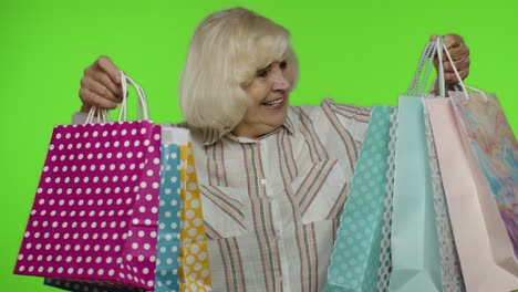 Senior-grandmother-raising-shopping-bags,-celebrating,-satisfied-with-purchase,-discount.-Chroma-key