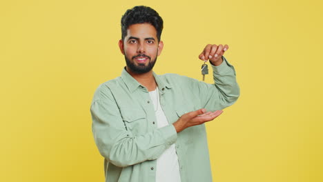 Indian-young-man-real-estate-agent-showing-keys-of-new-home-house-apartment,-buying-renting-property