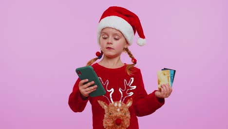 Child-girl-in-Christmas-sweateruse-mobile-cell-phone,-plastic-credit-bank-cards,-win,-calebrate,-wow