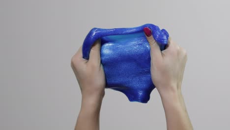 Woman-hands-playing-with-oddly-satisfying-blue-slime-gooey-substance.-Antistress