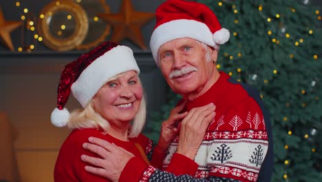 Smiling-married-senior-couple-grandparents-man-woman-in-living-room-celebrating-Christmas-together