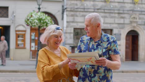 Senior-grandmother-and-grandfather-tourists-looking-for-a-place-to-go-in-new-city-using-paper-map