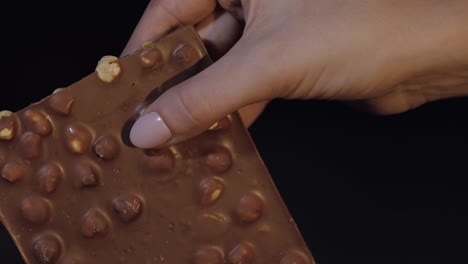 Schwarzer-Schokoladenriegel-In-Der-Hand-Einer-Frau,-Nahaufnahme