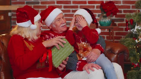 Großeltern-Schenken-Der-Erstaunten,-Glücklichen-Enkelin-Zu-Hause-Eine-Weihnachtsgeschenkbox-Und-Feiern