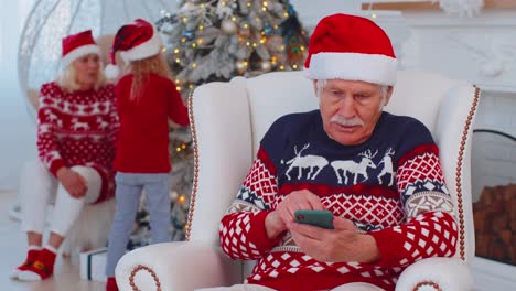 Senior-old-grandfather-man-buy-Christmas-gift-presents-doing-online-shopping-on-mobile-phone-at-home