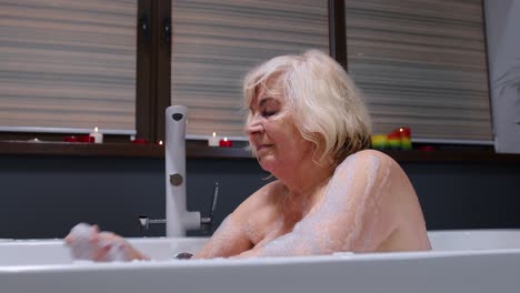 Beautiful-active-senior-woman-lying-in-warm-bath-with-bubbles,-enjoying-relaxation.-Elderly-people