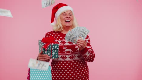 Ältere-Großmutter,-Die-An-Weihnachten-Geld-Ausgibt-Und-Geschenkboxen-Und-Einkaufstüten-Zum-Verkauf-Hält