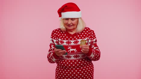 Mature-Christmas-grandmother-woman-use-mobile-cell-phone,-plastic-credit-bank-card-win-calebrate-wow