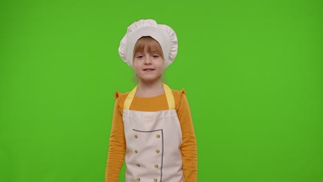 Child-girl-kid-cook-chef-baker-posing,-smiling,-showing-thumb-up-on-green-chroma-key-background