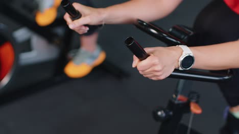 Close-up-athletic-woman-spinning-exercising-workout-on-stationary-cycling-machine-bike,-indoors