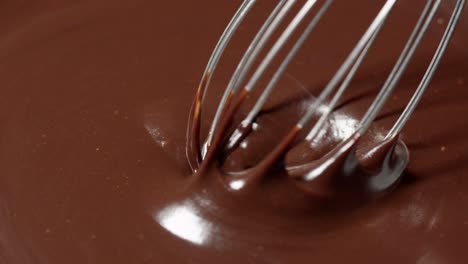 Slow-motion-mixing,-stirring-premium-dark-melted-chocolate-with-a-whisk,-process-of-making-sweets