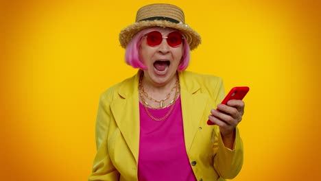Senior-woman-grandmother-with-mobile-phone-celebrating-winning-holiday-resort-vacation-tickets-pass