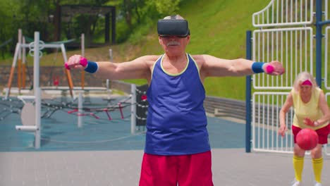 Senior-man-grandfather-in-VR-headset-do-sport-training-fitness-stretching-exercising-with-dumbbells