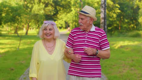 Senior-old-stylish-tourists-couple-grandmother,-grandfather-having-a-walk-and-talking-in-summer-park