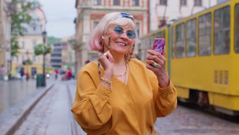 Älterer-Tourist-Mit-Retro-Fotokamera,-Lächelnd,-Musik-über-Kopfhörer-Hörend,-Auf-Der-Straße-Tanzend
