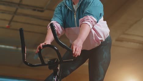 Healthy-Caucasian-woman-exercising-workout-on-stationary-cycling-machine-bike-in-gym,-Slow-Motion