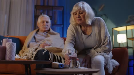 Senior-couple-grandfather-grandmother-at-home-during-covid19-coronavirus-taking-pills-drinking-water