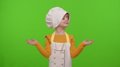 Child-girl-kid-dressed-cook-chef-in-apron-pointing-at-right-and-left-on-blank-space,-chroma-key