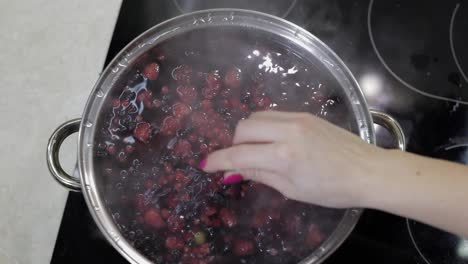 Stir-the-berries-in-pot-with-boiling-water.-Cooking-compote.-Kitchen
