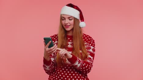 Woman-in-Christmas-sweater-looking-smartphone-display-sincerely-rejoicing-win-success-luck,-thumb-up
