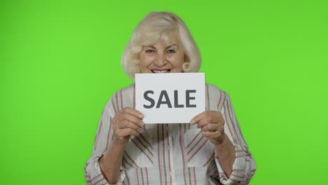 Ältere,-Stilvolle-Großmutter-Lächelt-Und-Hält-Ein-Banner-Mit-Der-Aufschrift-„Verkauf“.-Schwarzer-Freitag