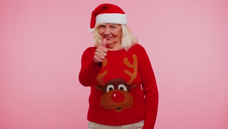 Grandmother-wears-red-New-Year-sweater-with-deers-raises-thumbs-up-agrees-with-something-good,-like