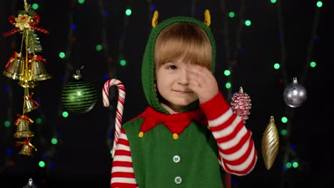 Mädchen-Im-Weihnachtselfenkostüm-Als-Weihnachtsmannhelfer-Winkt-Zur-Begrüßung-Mit-Der-Hand.-Hallo,-Hi,-Grußgeste