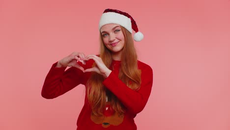 Lächelndes-Mädchen-Im-Weihnachtspullover-Macht-Herzgeste-Und-Zeigt-Zeichen-Der-Liebe,-Drückt-Gute-Gefühle-Aus