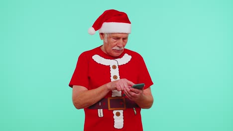 Grandfather-in-Christmas-t-shirt-looking-smartphone-display-sincerely-rejoicing-win-success-luck