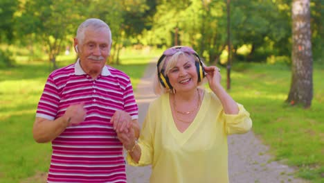 Elderly-stylish-couple-family-grandmother-grandfather-dancing-walking-listening-music-in-summer-park
