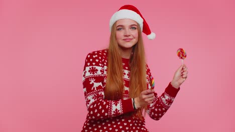 Joyful-girl-in-Christmas-sweater,-hat-holding-candy-striped-lollipops,-dancing,-making-silly-faces