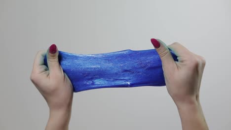 Woman-hands-playing-with-oddly-satisfying-blue-slime-gooey-substance.-Antistress