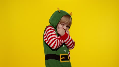 Scared-kid-girl-in-Christmas-elf-Santa-helper-costume-looking-aafraid,-hiding-face-with-hands