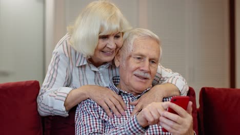 Älteres-Großelternpaar,-Das-Zu-Hause-Telefoniert-Und-Ein-Digitales-Mobiltelefon-Benutzt.-Coronavirus-Lockdown