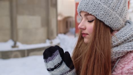 Close-up-of-young-tourist-woman-warming-her-cold-hands-outdoors-in-winter-day-on-street-in-city