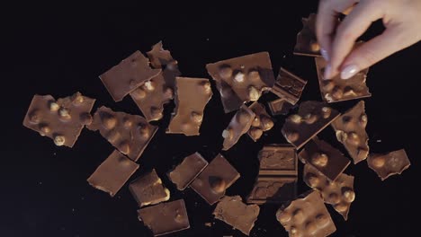 Die-Hand-Einer-Frau-Nimmt-Ein-Stück-Schokolade-Aus-Einem-Haufen-Schokoladenstücke
