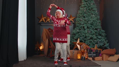 Elderly-family-couple-grandmother-grandmother-dancing-at-decorated-home-room-with-Christmas-tree