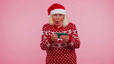 Besorgte-Großmutter-Im-Weihnachtspullover-Spielt-Begeistert-Rennvideospiele-Auf-Dem-Handy
