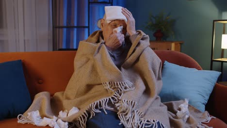Senior-grandfather-man-suffering-from-cold-or-allergy,-blows-nose-snot-into-napkin-sitting-at-home