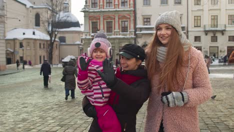 Two-young-smiling-women-tourists-with-adoption-child-girl-walking-at-famous-sights-of-old-city