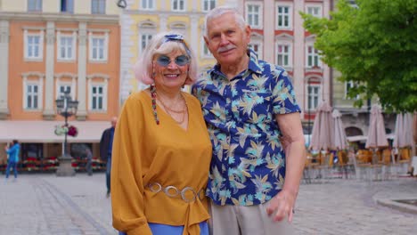 Elderly-stylish-couple-tourists-man-woman-looking-approvingly-at-camera-showing-ok-gesture-like-sign