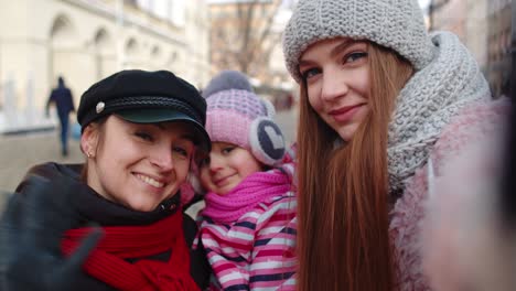 Women-tourists-taking-selfie-photos-on-mobile-phone-with-adoption-child-girl-on-winter-city-street