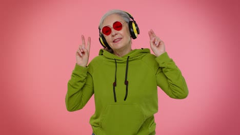 Senior-woman-listening-music-on-headphones-dancing-disco-fooling,-having-fun,-gesticulating-hands