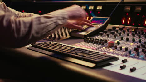 Audio-technician-uses-mixing-console-and-faders-in-control-room