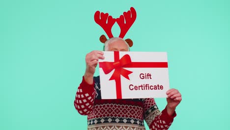 Senior-grandfather-man-in-New-Year-sweater-presenting-card-gift-certificate-coupon-winner-voucher